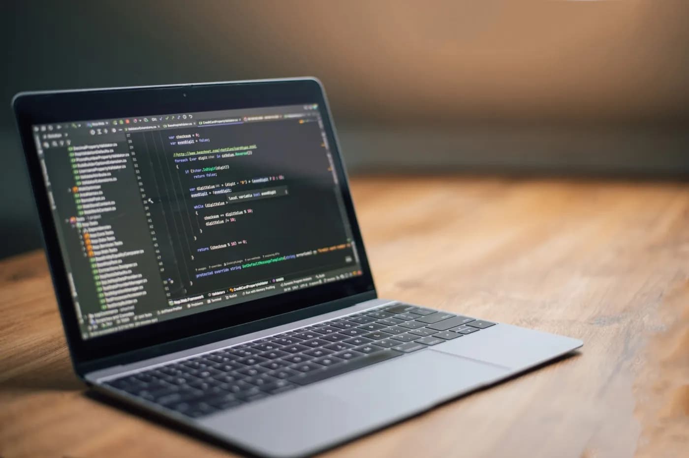 A laptop on a wooden desk showing real code in an editor